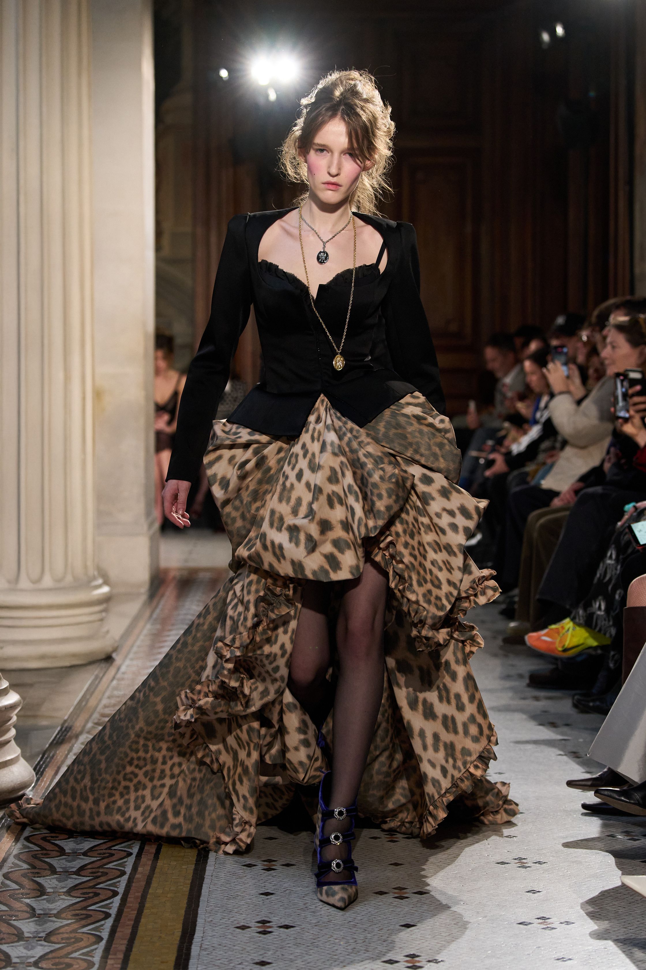 这一季 Nina Ricci 在经典巴黎优雅中加入更具戏剧张力的女性表达：黑色立体蝴蝶结装饰、豹纹雪纺长裙与结构西装形成鲜明对比，柔软与力量交织。轻薄面料与不对称层叠裙摆让整体轮廓更具流动感，既保留品牌浪漫基因，又带出一种现代女性的自信与锋芒-顽石频道趋势研究